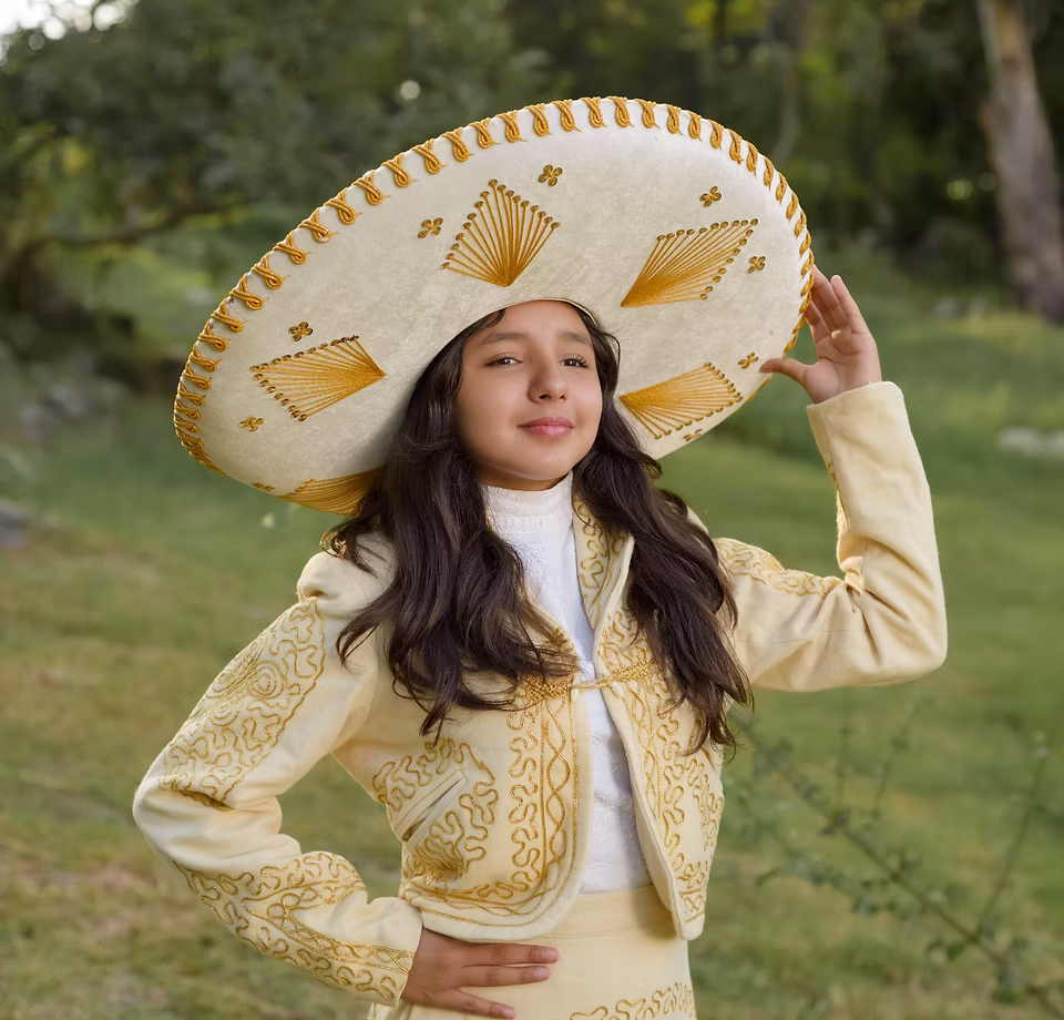 Participant in traditional Mariachi attire holding an instrument, showcasing cultural heritage
